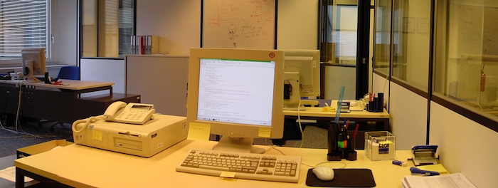 Mon bureau en 2005: grand bureau, petit écran, matériel beige, stylos, papier, post-its